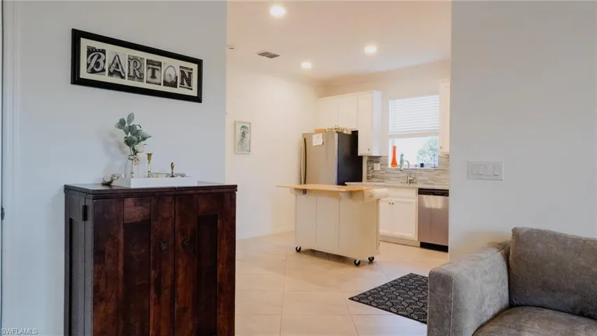 Kitchen featuring tasteful backsplash, white cabinetry, stainless steel appliances, light tile patterned floors, and a center island