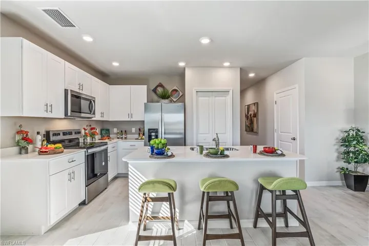 Kitchen with a kitchen bar, an island with sink, light wood-type flooring, and appliances with stainless steel finishes