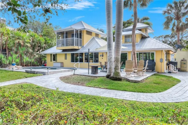 Back of house with a balcony, a yard, and a patio