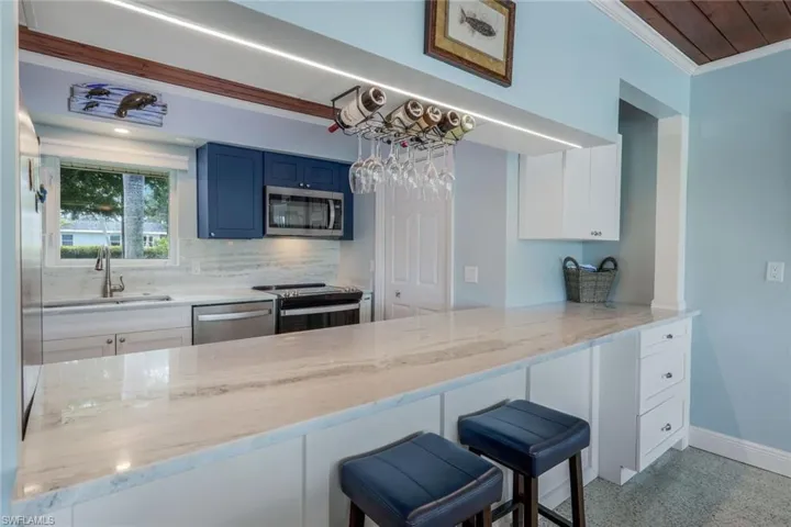 Kitchen with appliances with stainless steel finishes, blue cabinetry, a kitchen breakfast bar, and kitchen peninsula