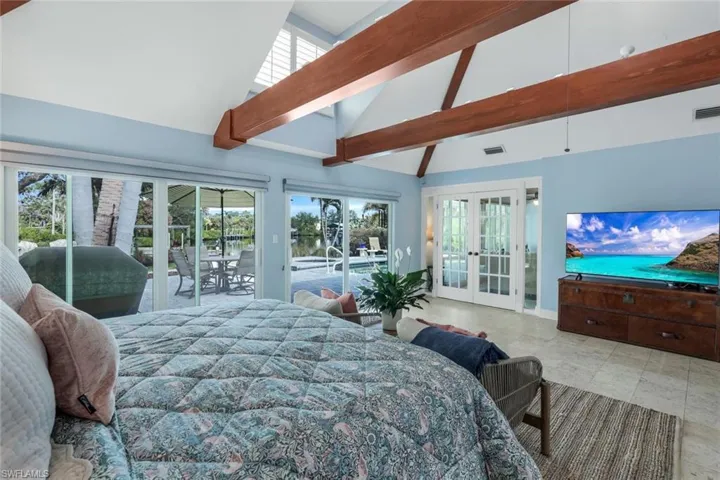 Primary Bedroom with multiple windows, access to pool, high vaulted ceiling, and french doors