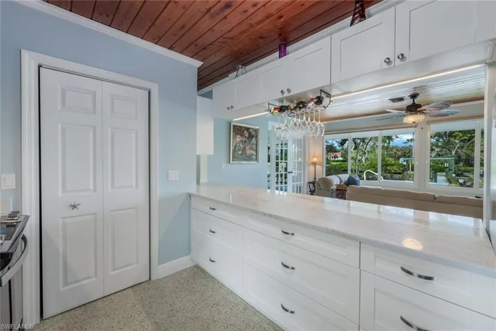 Kitchen with white cabinetry, ornamental molding, wood ceiling, and light stone countertops