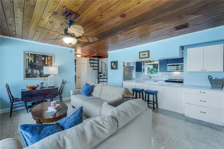 Living room featuring ornamental molding, wooden ceiling, and ceiling fan