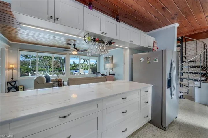 Kitchen featuring white cabinetry, stainless steel fridge, light stone countertops, and wooden ceiling