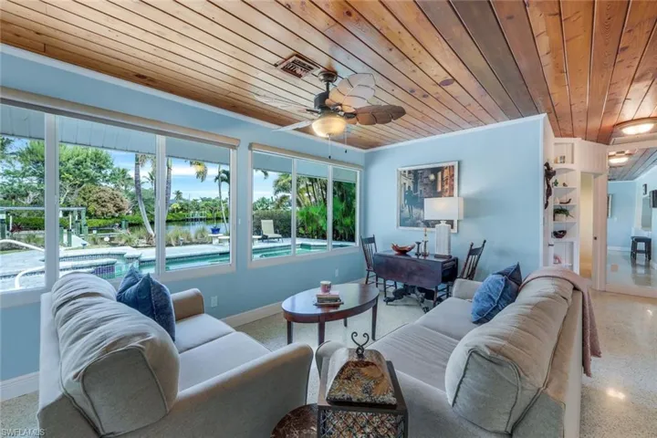 Living room with crown molding, wooden ceiling, a healthy amount of sunlight, and a water view