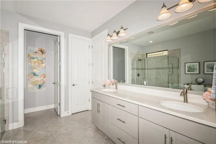 Bathroom with dual vanity, an enclosed shower, and tile patterned flooring