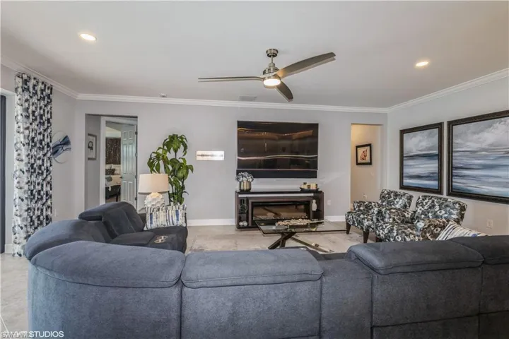 Living room with ceiling fan, ornamental molding, and light tile patterned floors