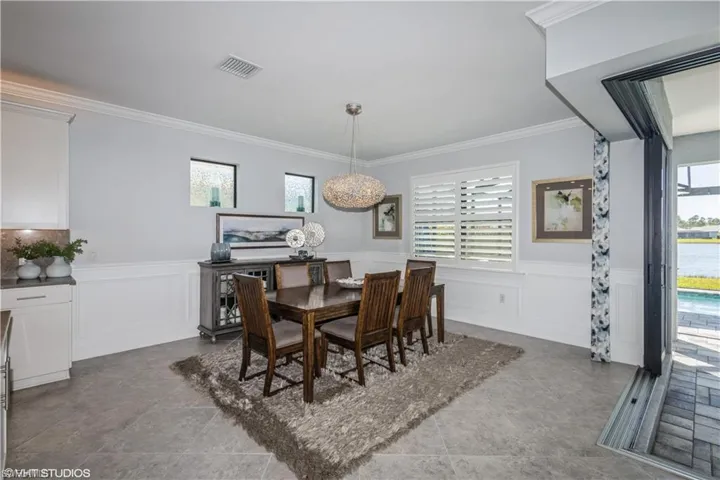 Tiled dining room featuring plenty of natural light and ornamental molding