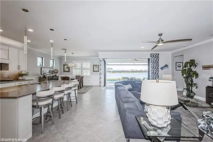 Living room featuring ceiling fan, sink, light tile patterned floors, and crown molding