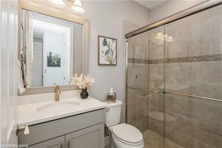 Bathroom featuring vanity, a shower with door, and toilet