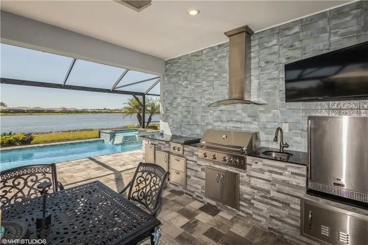 Kitchen featuring tile walls, sink, wall chimney range hood, fridge, and dark tile patterned flooring