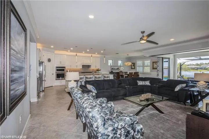 Living room featuring ornamental molding, light tile patterned floors, and ceiling fan
