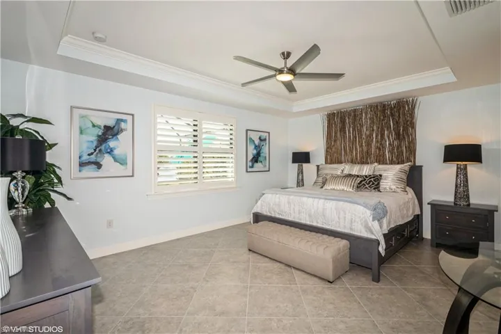 Tiled bedroom with ceiling fan and a raised ceiling