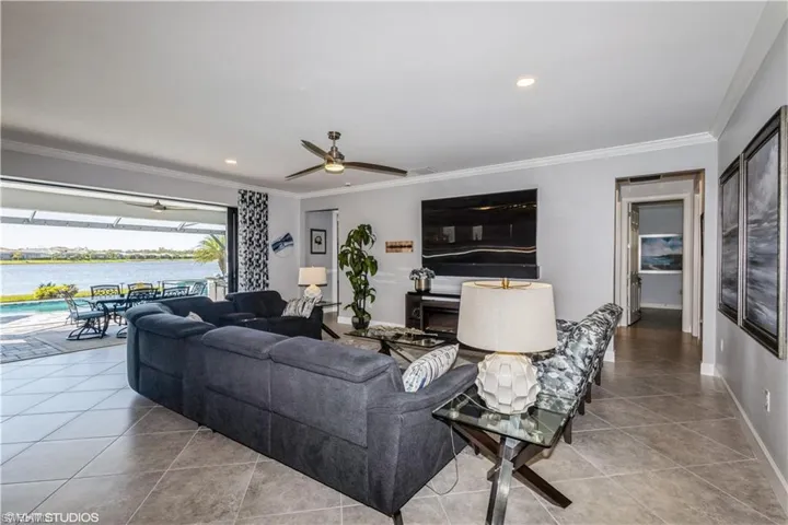 Tiled living room featuring ceiling fan, a water view, and ornamental molding