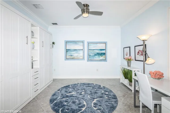 Living area featuring light tile patterned floors, crown molding, and ceiling fan
