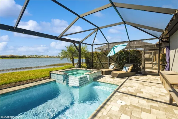 View of swimming pool featuring a lanai, an in ground hot tub, and a patio area