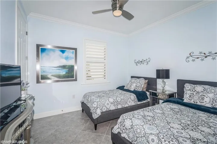 Tiled bedroom with ceiling fan and crown molding