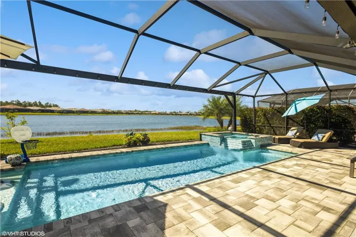 View of pool with a patio area, an in ground hot tub, a water view, and glass enclosure