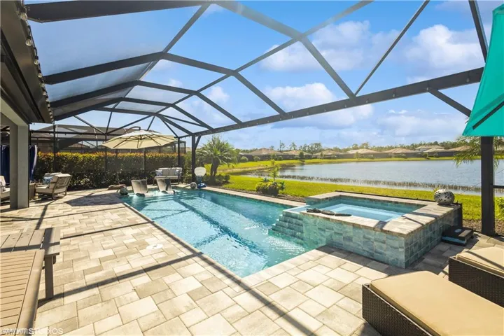 View of pool featuring a lanai, an in ground hot tub, a patio area, and a water view