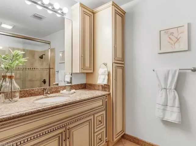 Full bath with vanity, a shower stall, and light tile patterned floors
