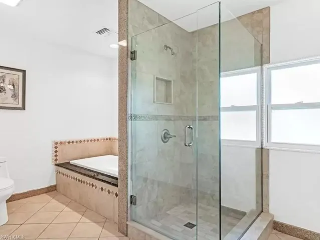 Full bath with light tile patterned flooring, a bath, and a shower stall