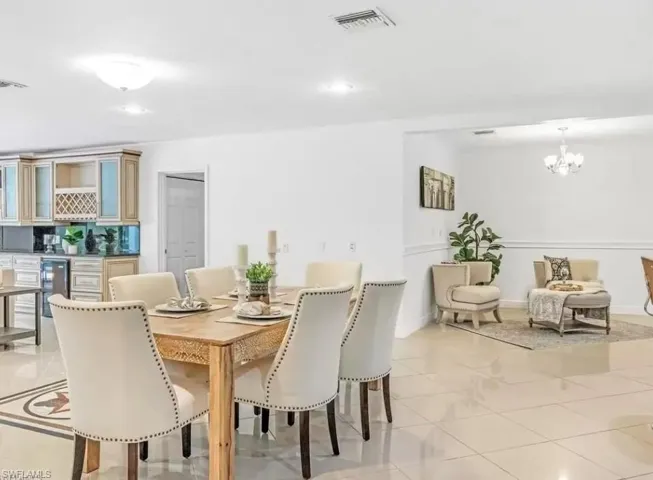 Dining area with light tile patterned flooring, beverage cooler, a chandelier, and recessed lighting