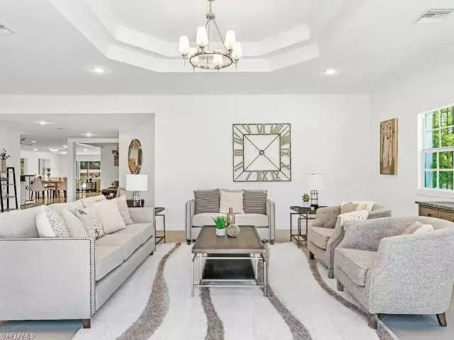 Living room featuring plenty of natural light, recessed lighting, a raised ceiling, and a chandelier