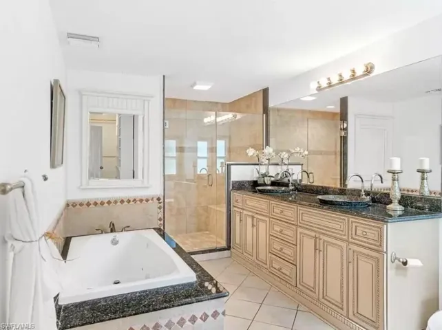 Full bath featuring a bath, double vanity, a shower stall, and light tile patterned flooring