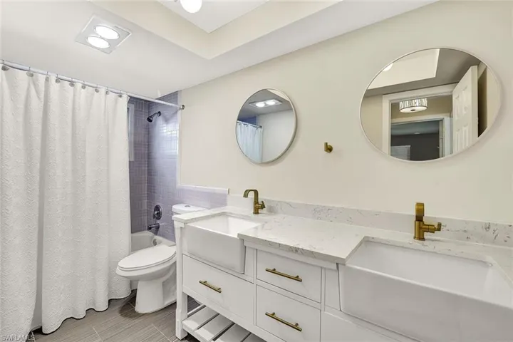 En suite primary bathroom features dual sinks and quartz countertops.