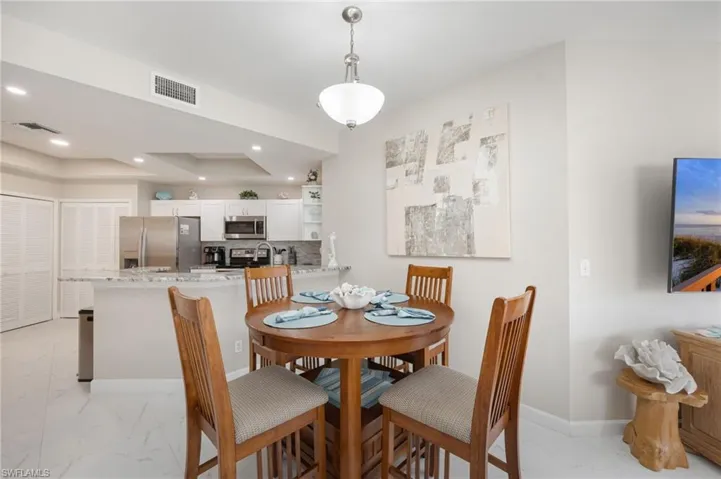 Dining area with light marble finish flooring, a raised ceiling, and recessed lighting