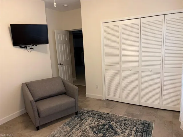 White louvered closet doors with round knobs, light-toned wall paint, and neutral floor tiling