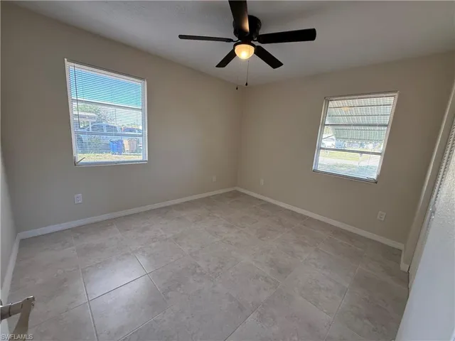 Empty room featuring ceiling fan and light tile patterned floors