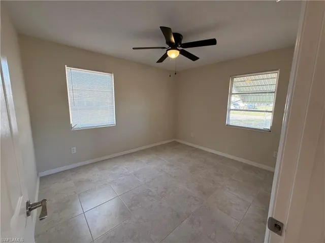 Empty room with a ceiling fan and light tile patterned floors