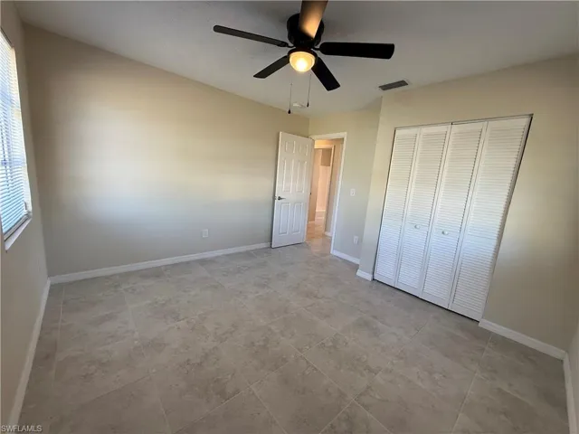 Unfurnished bedroom with ceiling fan and a closet