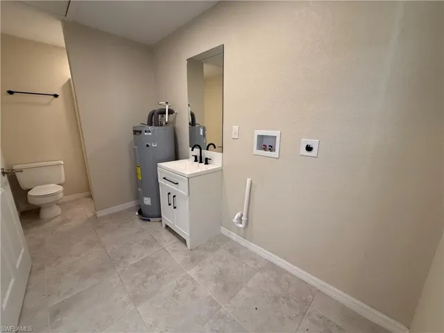 Laundry room with electric water heater, hookup for a washing machine, and hookup for an electric dryer