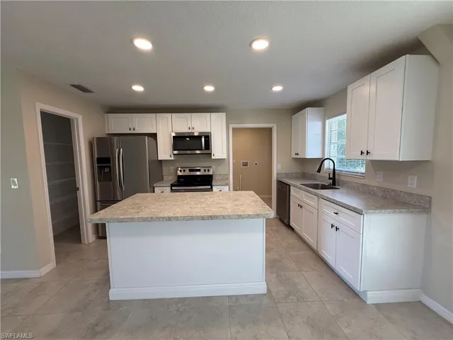 Kitchen with light countertops, stainless steel appliances, white cabinets, recessed lighting, and a textured ceiling