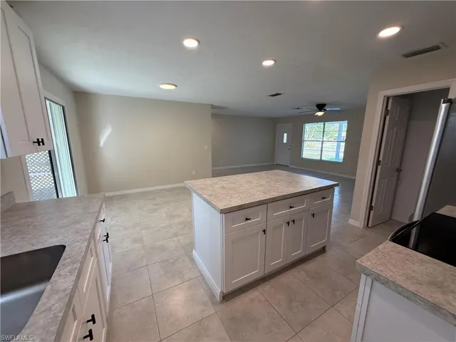 Kitchen with open floor plan, white cabinetry, light countertops, and recessed lighting