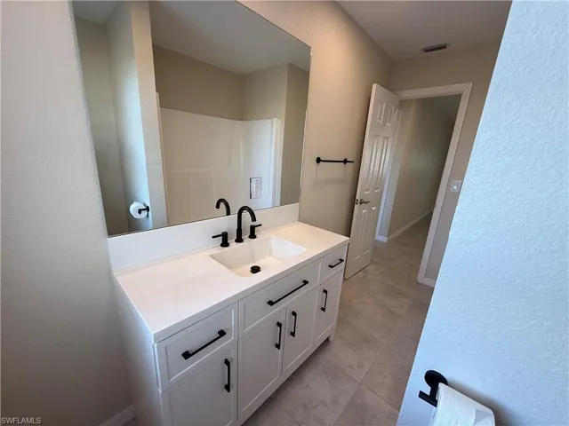 Full bath with a textured wall and vanity