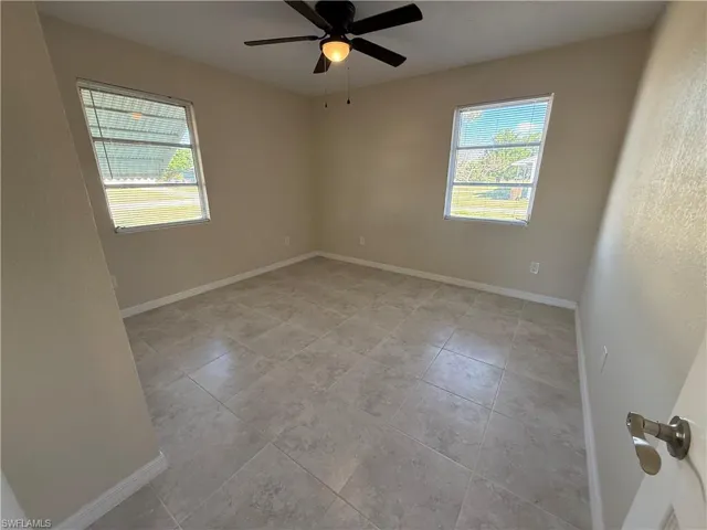 Unfurnished room featuring ceiling fan, light tile patterned flooring, and a textured wall