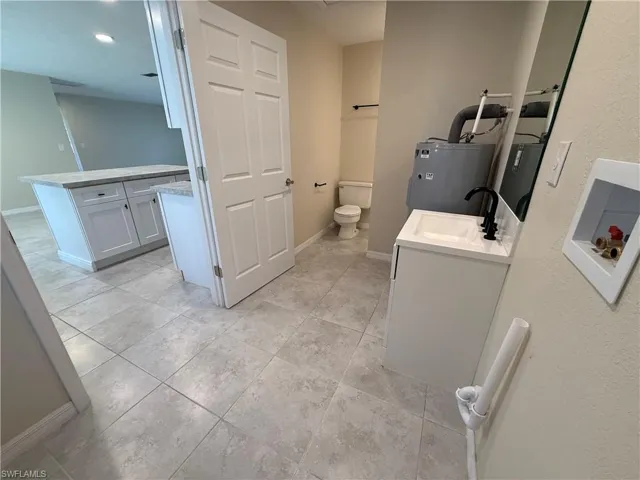 Full bath featuring vanity, electric water heater, water heater, light tile patterned flooring, and recessed lighting