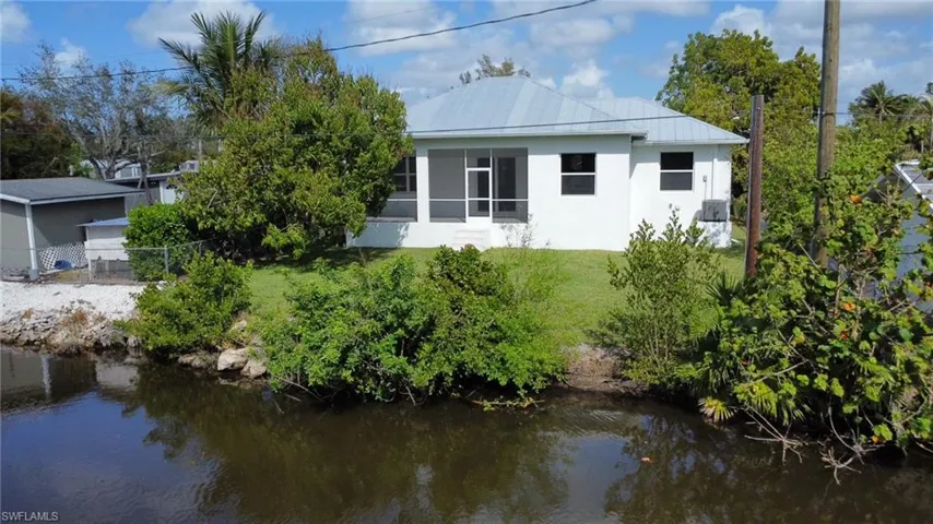 Rear view of house featuring a water view and a yard