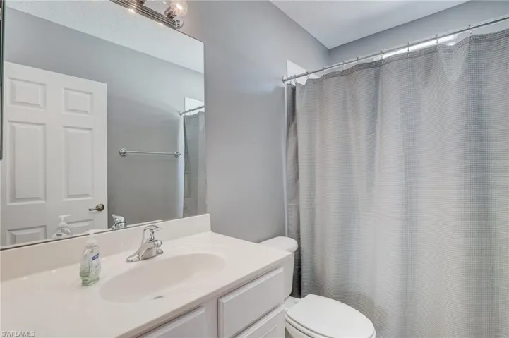 Bathroom with a shower with curtain, vanity, and toilet
