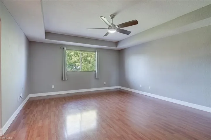 Master bedroom featuring ceiling fan, a raised ceiling, light hardwood / wood-style floors, and a textured ceiling
