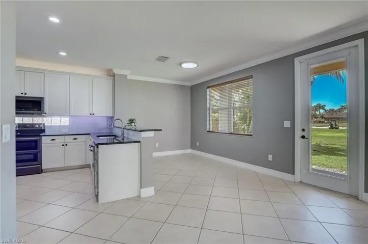 Kitchen with white cabinetry, backsplash, kitchen peninsula, and appliances with stainless steel finishes