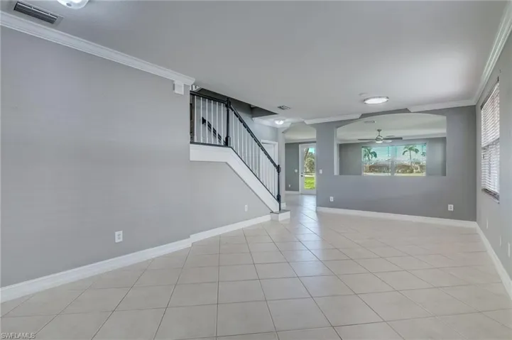 Living room with ornamental molding, ceiling fan, and light tile patterned flooring