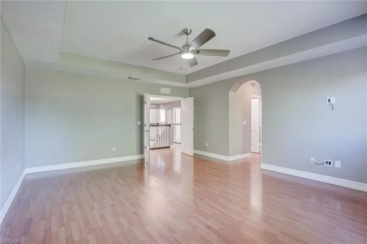 Master bedroom featuring ceiling fan, a tray ceiling, and light hardwood / wood-style floors