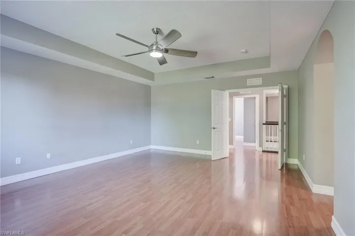 Master bedroom with a tray ceiling, light hardwood / wood-style floors, and ceiling fan