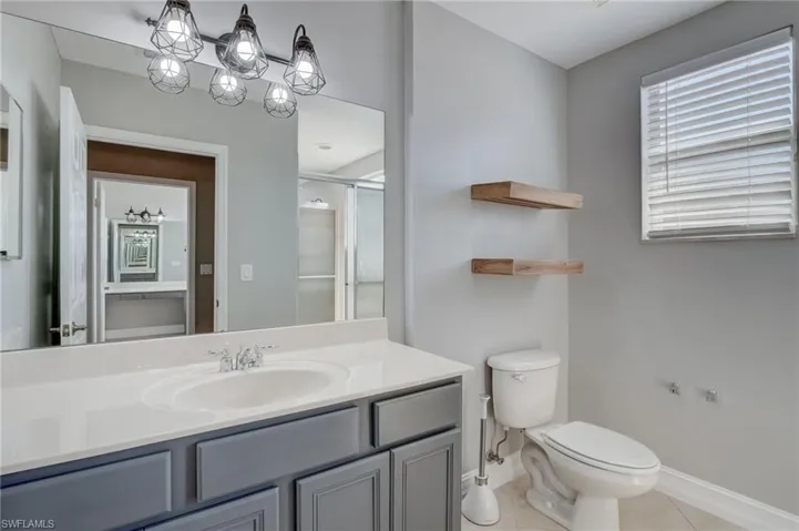 Master bathroom with an inviting chandelier, vanity, tile patterned floors, toilet, and walk in shower
