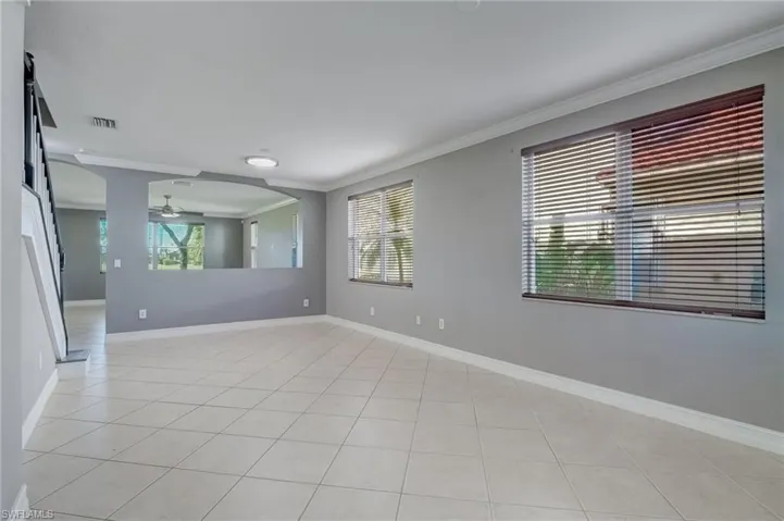 Front room featuring ceiling fan, light tile patterned floors, ornamental molding, and a healthy amount of sunlight