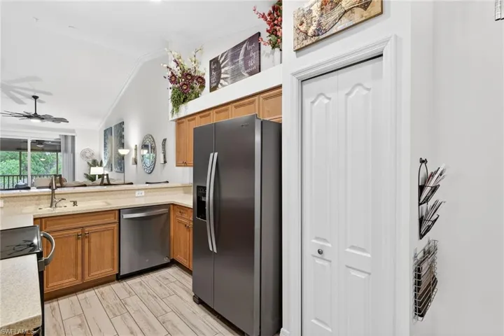Kitchen with brown cabinets, stainless steel appliances, crown molding, ceiling fan, and lofted ceiling